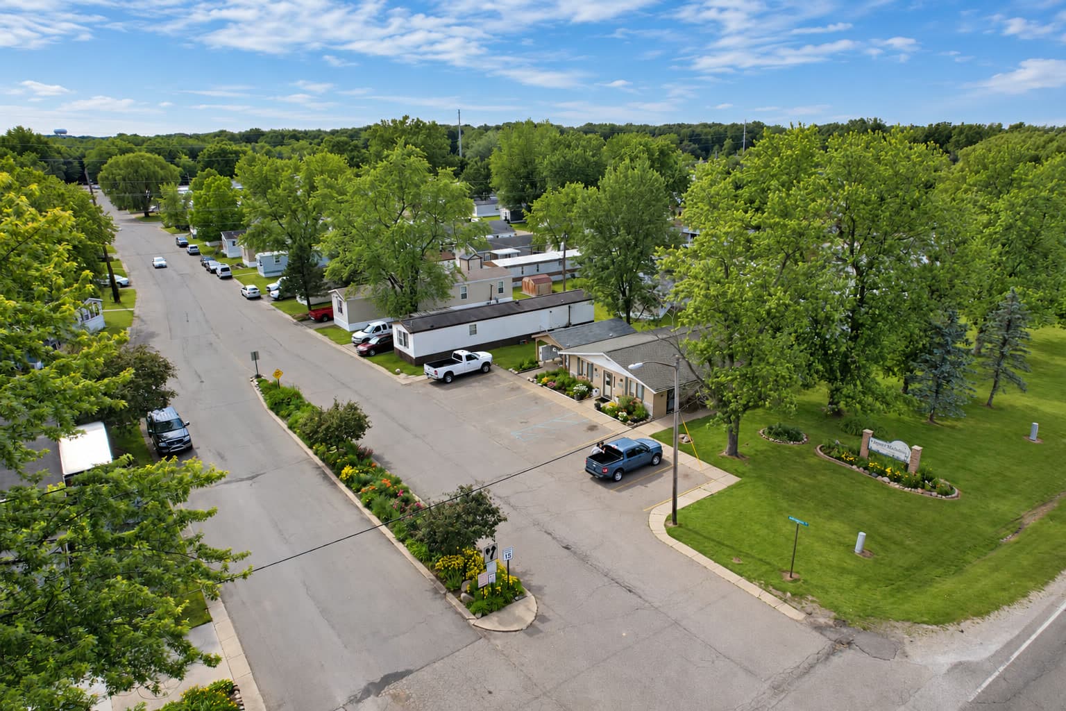 Aerial view of the Lapeer Meadows entrance, homes, and mature trees